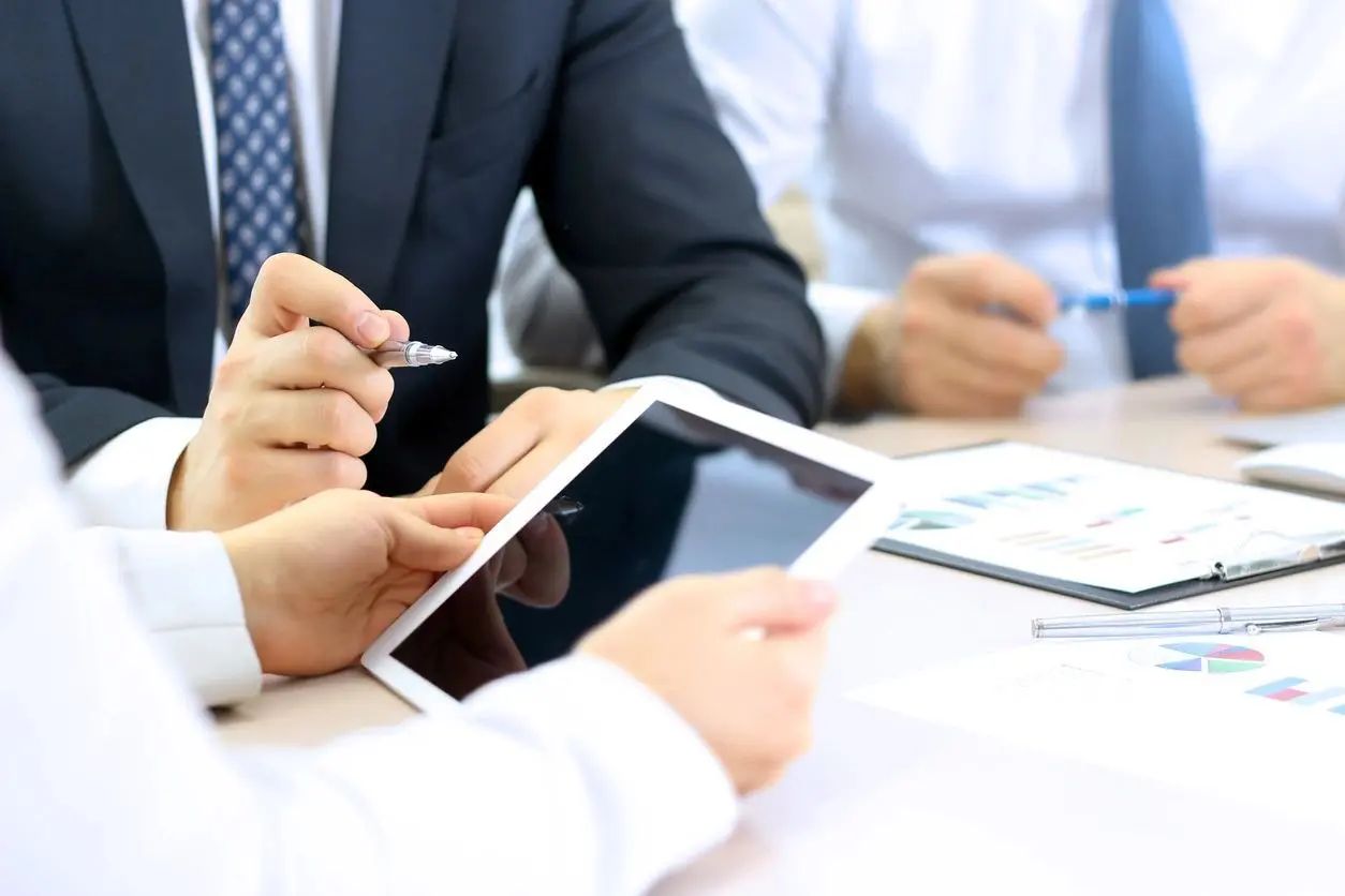 A group of people sitting at a table with two ipads.