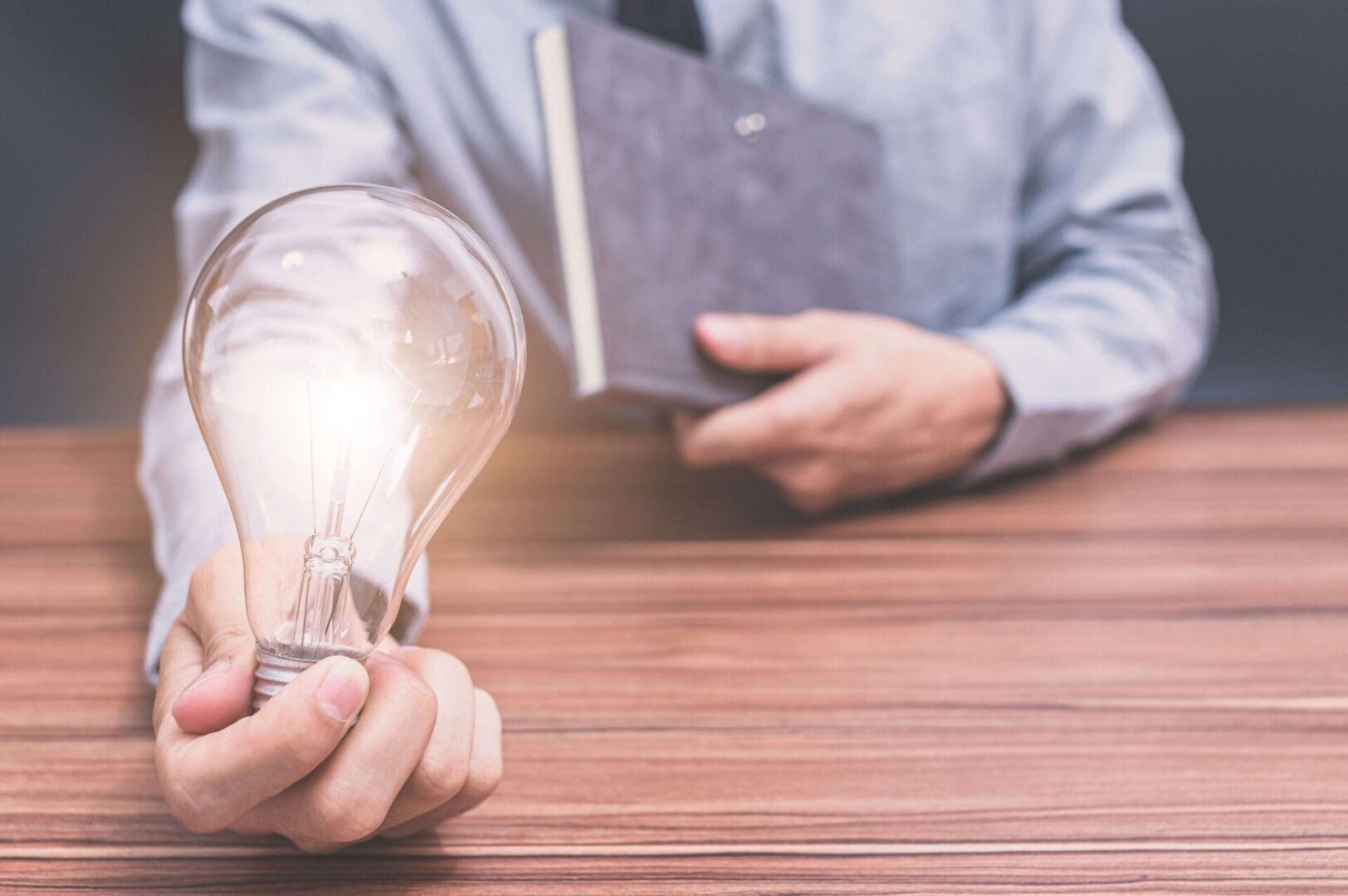 A person holding an open light bulb and reading a book.