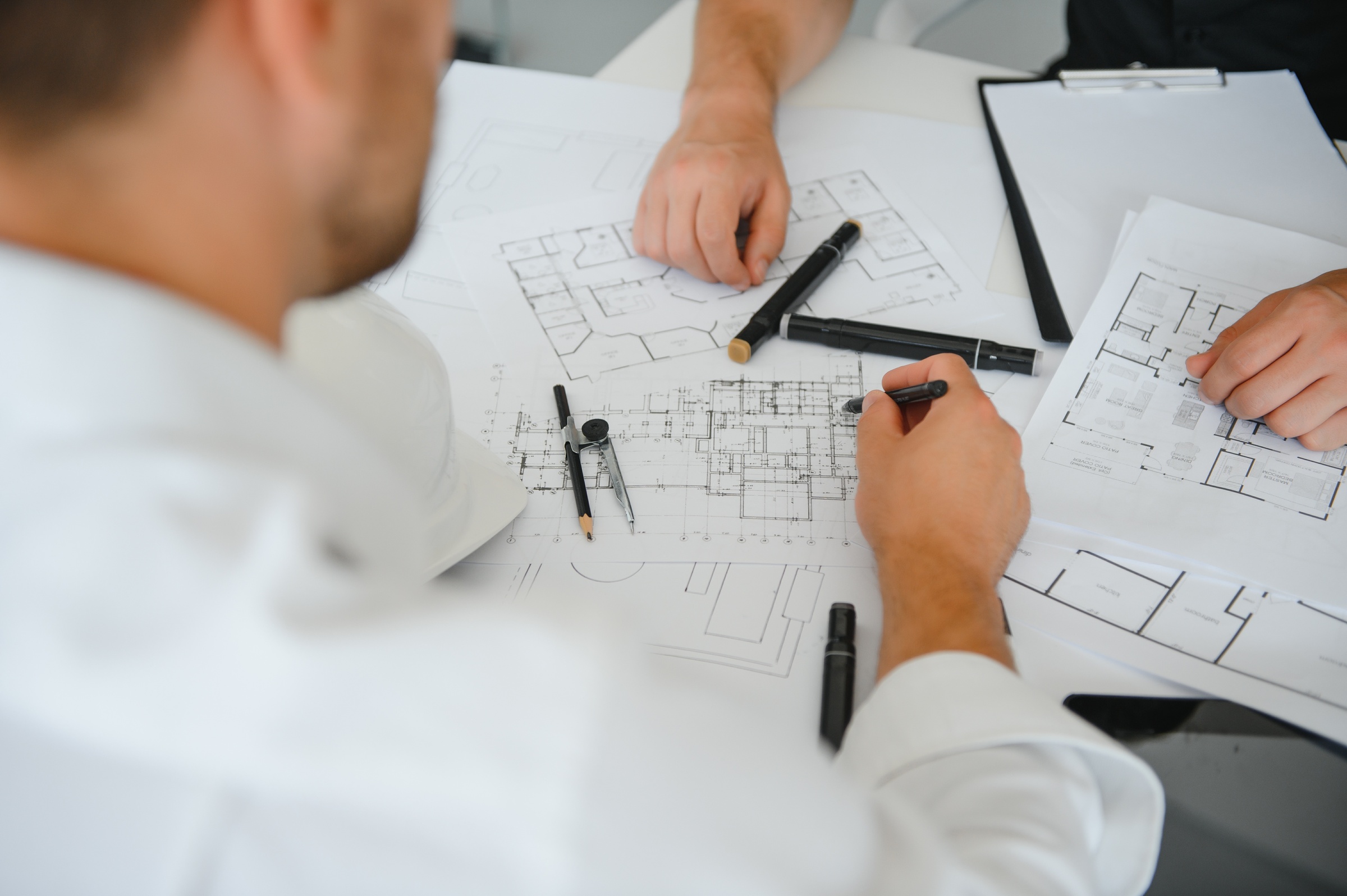 AEC professionals reviewing architectural drawings together to coordinate design decisions and systems during organizational change in the Architectural, Engineering, and Construction industry.