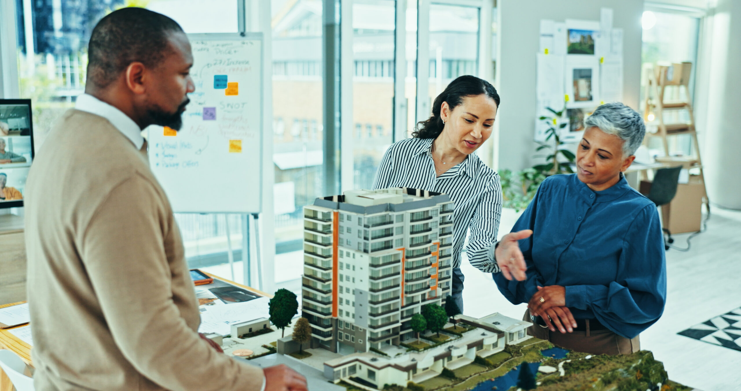 Construction leadership team collaborating around an architectural model during an organizational change planning session.
